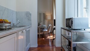 Une cuisine moderne dotée d’un plan de travail en marbre, d’un four à micro-ondes, d’une bouilloire et d’un coin repas avec une chaise et une table.