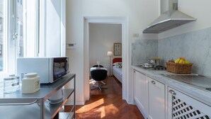 Une cuisine moderne équipée d’un four à micro-ondes, d’une machine à café et d’un panier de fruits posé sur le plan de travail.