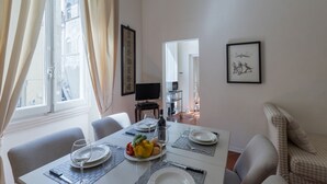 Comedor con una mesa preparada para cuatro, televisión y obras de arte en las paredes.