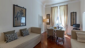 Un salon comprenant un canapé, une table à manger avec des chaises, une lampe et des œuvres d’art accrochées aux murs.