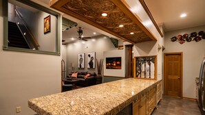 A kitchen with granite countertops, wooden cabinets, and a ceiling with intricate woodwork.