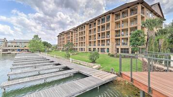 A hotel with multiple balconies, a dock extending into a body of water, and a well-maintained lawn area.
