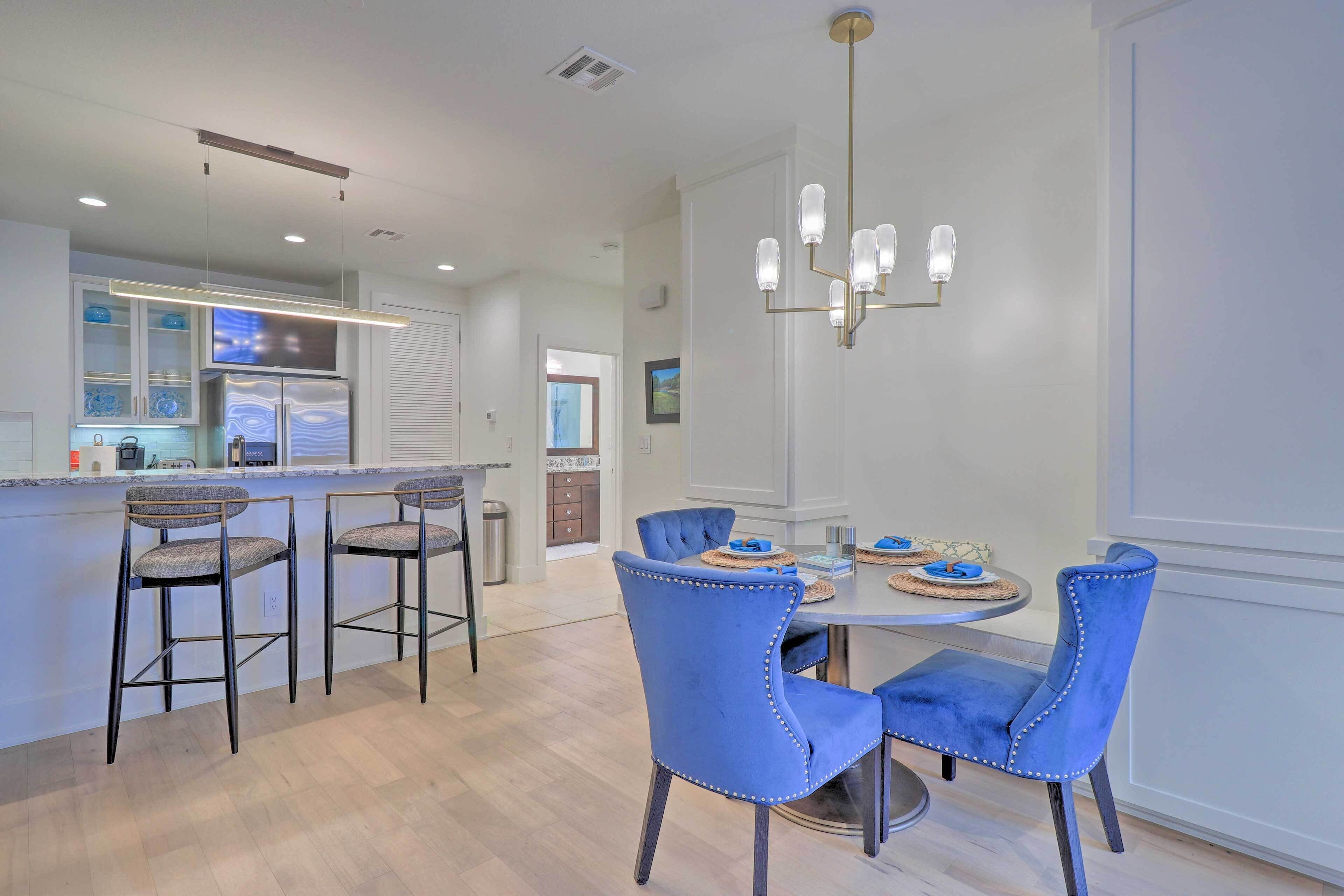 A modern kitchen with a central island, bar stools, and a dining table with chairs.