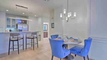 A modern kitchen with a central island, bar stools, and a dining table with chairs.