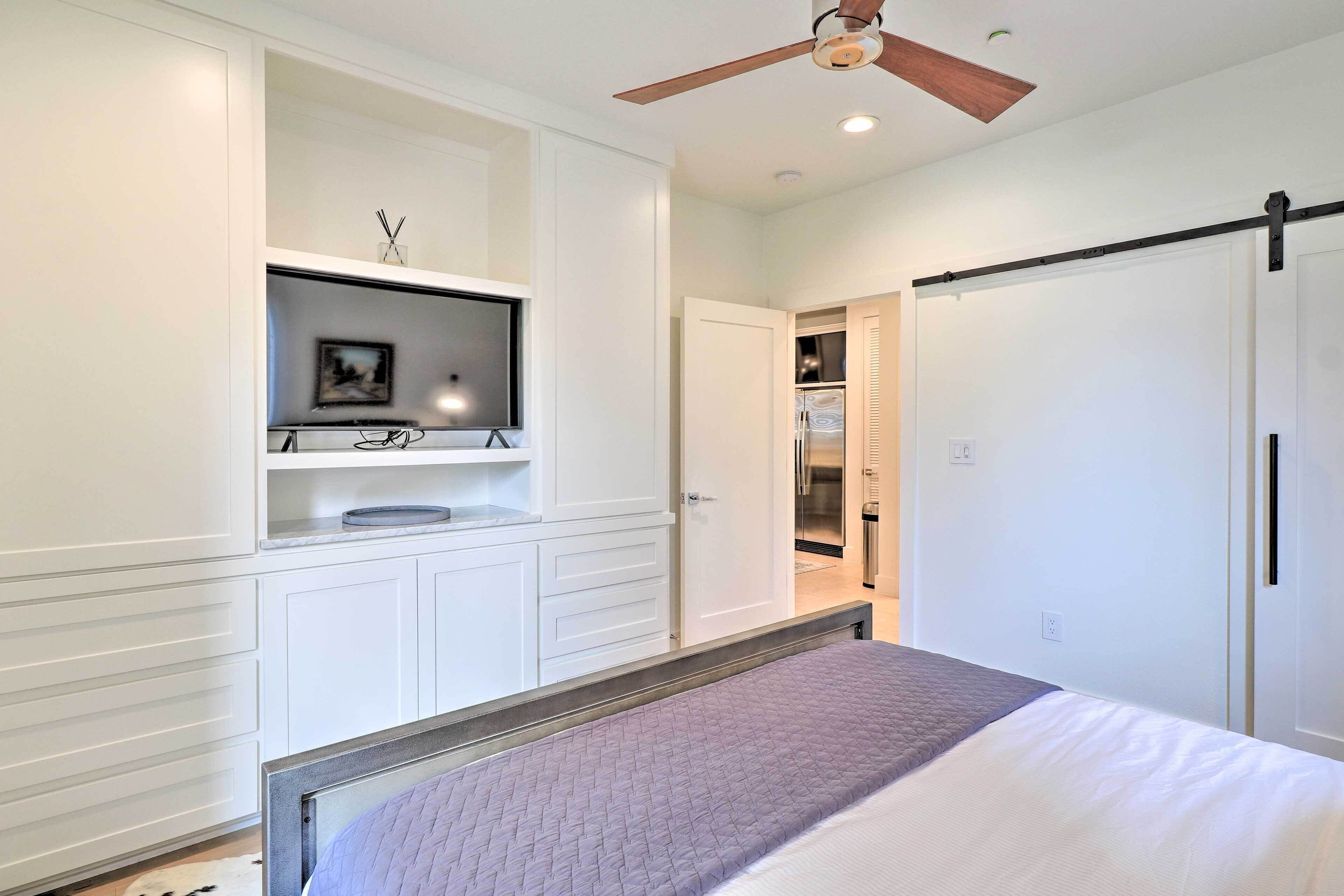 A bedroom with a bed, a ceiling fan, built-in shelving, and a wardrobe.