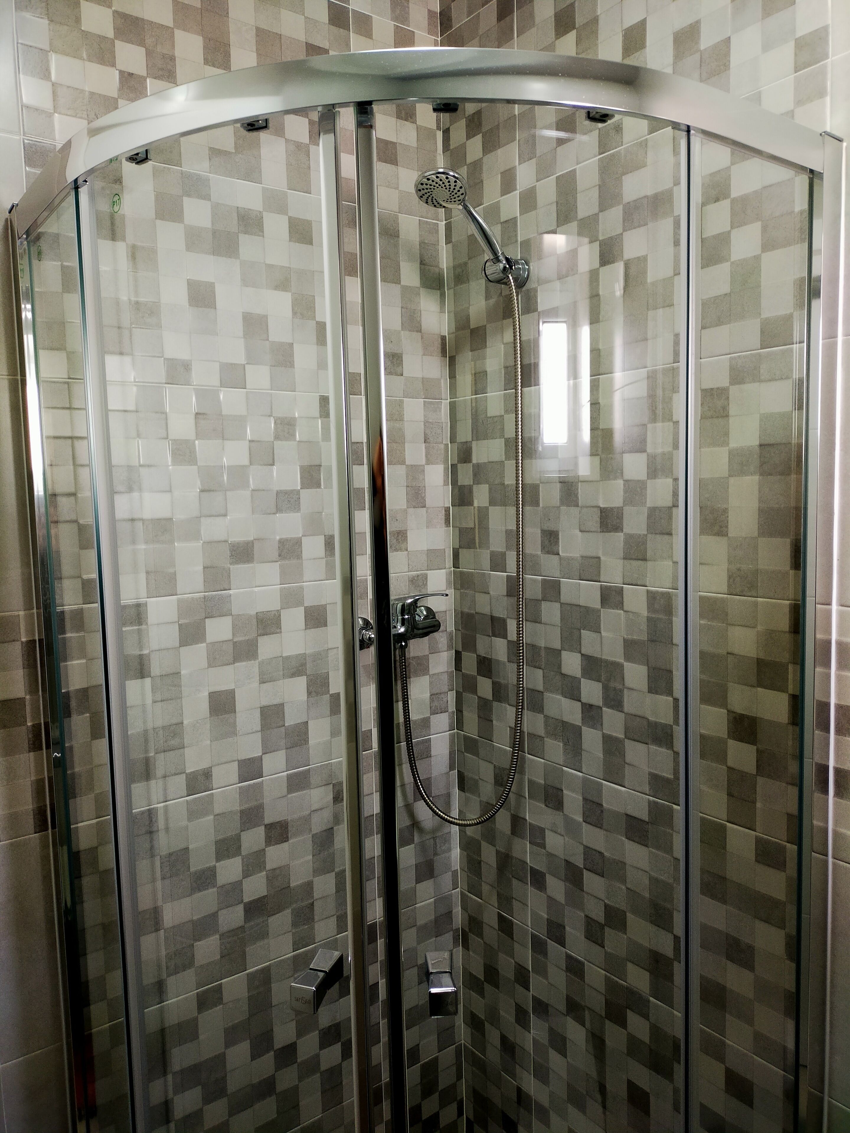 A glass-enclosed shower with a checkered tile pattern on the walls.