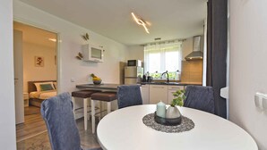 Une cuisine moderne équipée d’un réfrigérateur, d’un four à micro-ondes et d’une cuisinière. On y trouve également un coin repas avec une table ronde et quatre chaises.