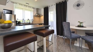 Une cuisine moderne avec un coin bar, une table à manger avec des chaises et une horloge murale décorative.