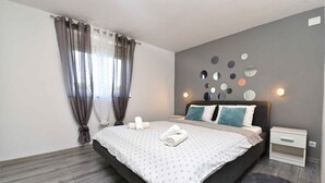 Une chambre moderne avec un grand lit, des murs gris et un plancher en bois.