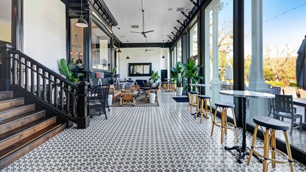 A spacious indoor area with a tiled floor, a staircase, and large windows offering a view of the outdoors. - Poolside Retreat | Patio | 10 Min to DT (Napa)