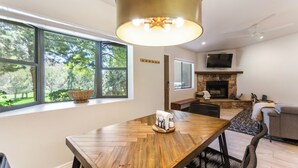 Una sala de estar moderna con una mesa de comedor de madera, una chimenea de piedra y un televisor montado encima.