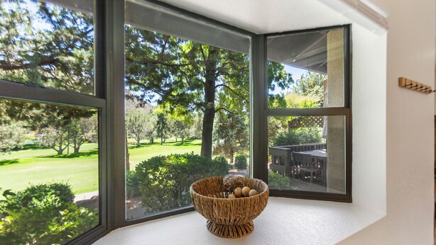 Una ventana en esquina con una cesta tejida que contiene huevos sobre un alféizar blanco.