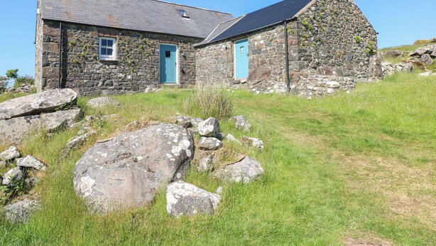 A stone house with a blue door and a sloped roof. - Ty Mellen (Newport)