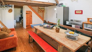A cozy kitchen with wooden beams, a dining table with benches, a refrigerator, and a sign for Lockwoods. - Ty Mellen (Newport)