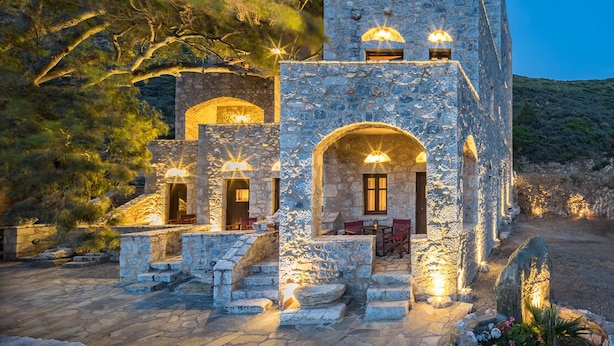 Um edifício de pedra com arcadas e janelas, iluminado por luzes quentes.
