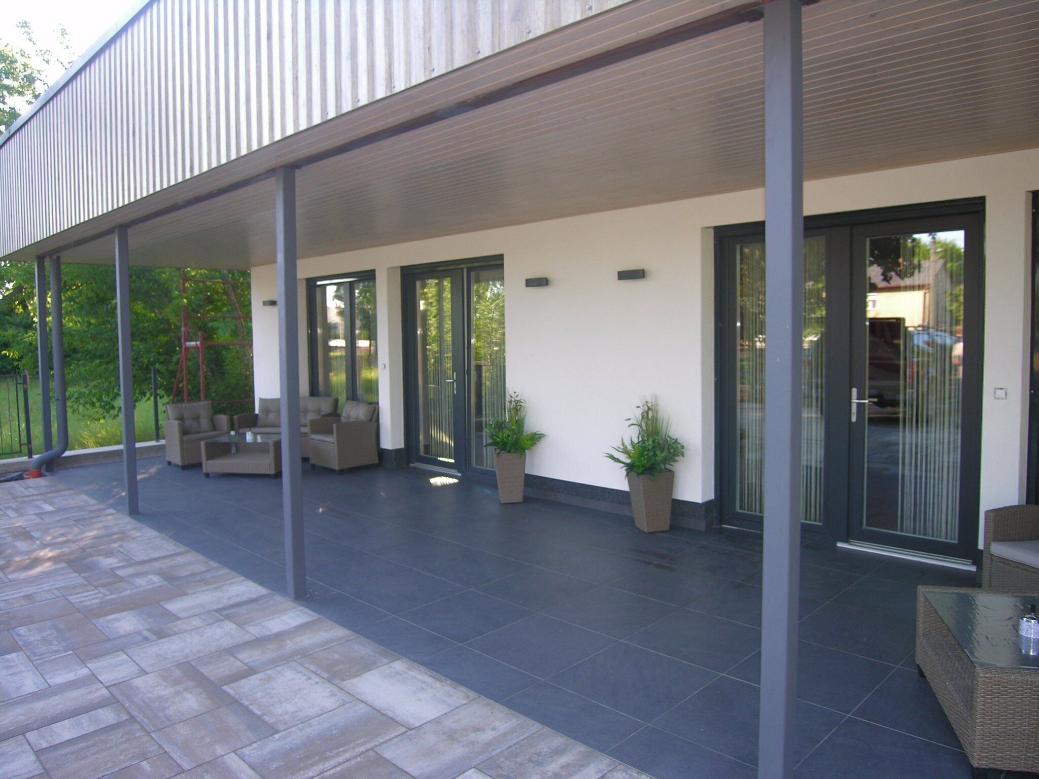 A covered outdoor area with a patio, seating, and potted plants.