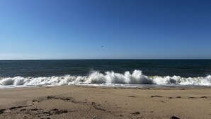 A beach with waves crashing onto the shore under a clear blue sky. - Chappaquiddick Getaway with stunning Ocean Views, walk to the beach (Edgartown)