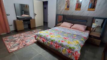 A bedroom with a bed, bedside tables, a dresser, a mirror, and a ceiling light fixture.