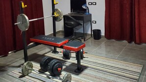 Et hjemmegym med bænkpres, squat stativ og forskelligt vægtudstyr.