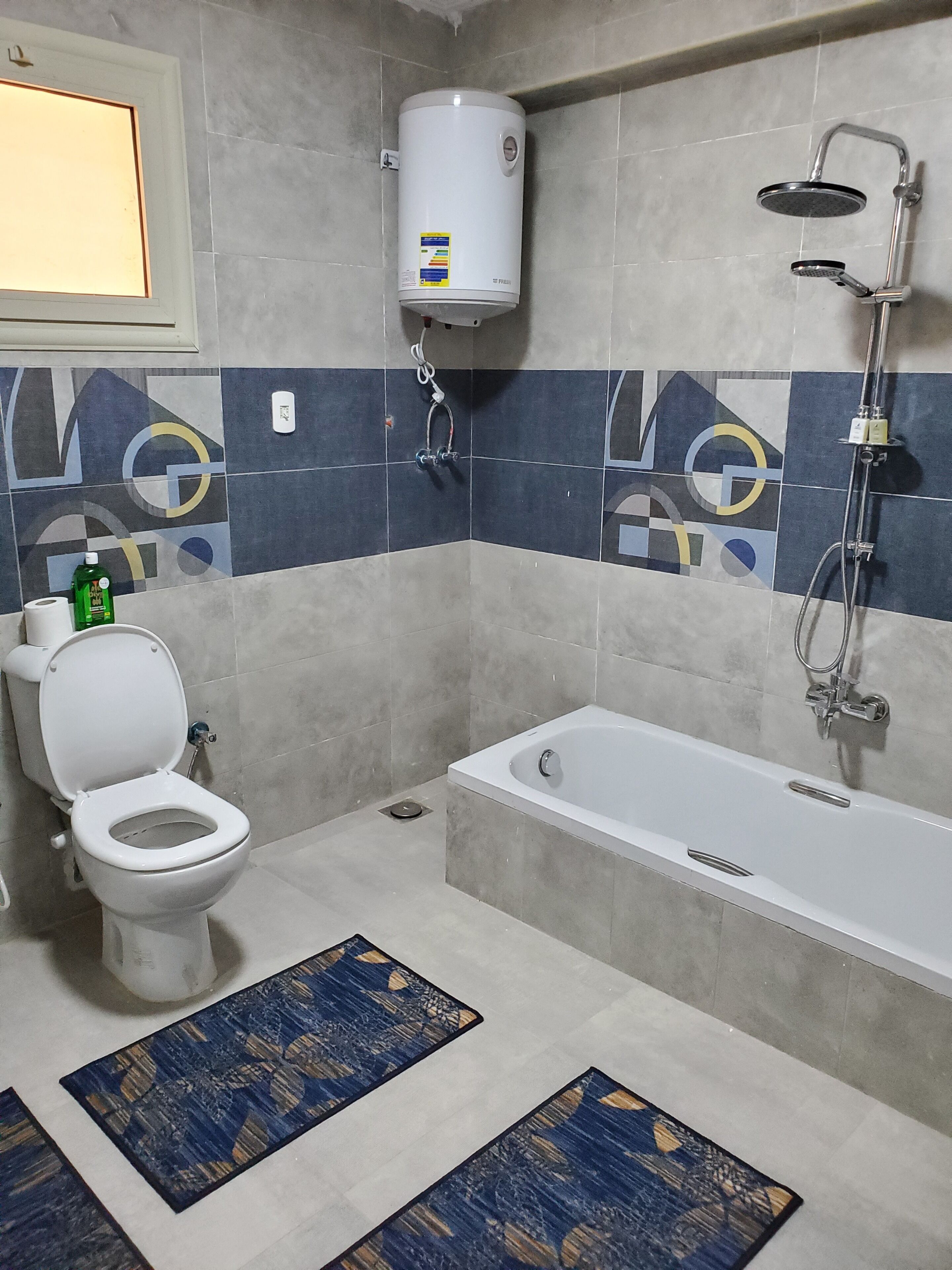 A bathroom with a toilet, bathtub, shower, and a water heater.