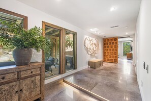 Ein modernes Interieur mit Kamin aus Stein, einer großen Pflanze im Topf und einer hölzernen Bank.
