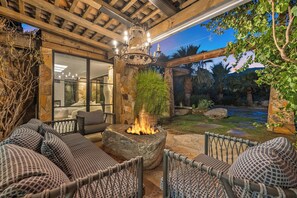 Eine Außenpatio mit Steinsitzgelegenheiten, einer Feuerstelle und Blick auf einen Garten.