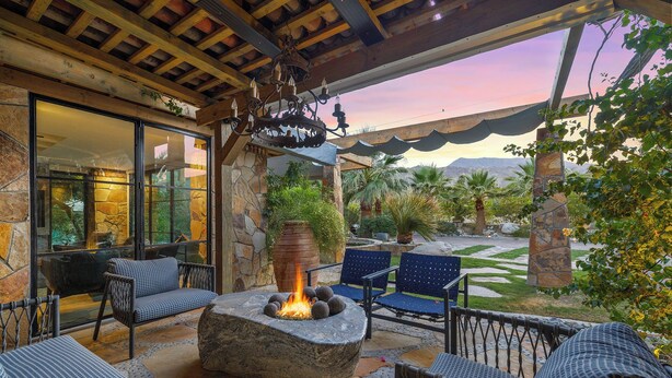 Un patio al aire libre con asientos de piedra, un pozo de fuego y vistas a un paisaje montañoso.