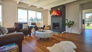 Una sala de estar moderna con sofás de cuero, una mesa de centro redonda, chimenea y ventanas grandes.