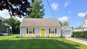 A single-story house with a yellow front door, two windows on the first floor, and a garage on the right.