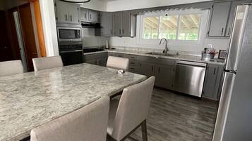 A modern kitchen with a large island, stainless steel appliances, and a view of the outdoors.