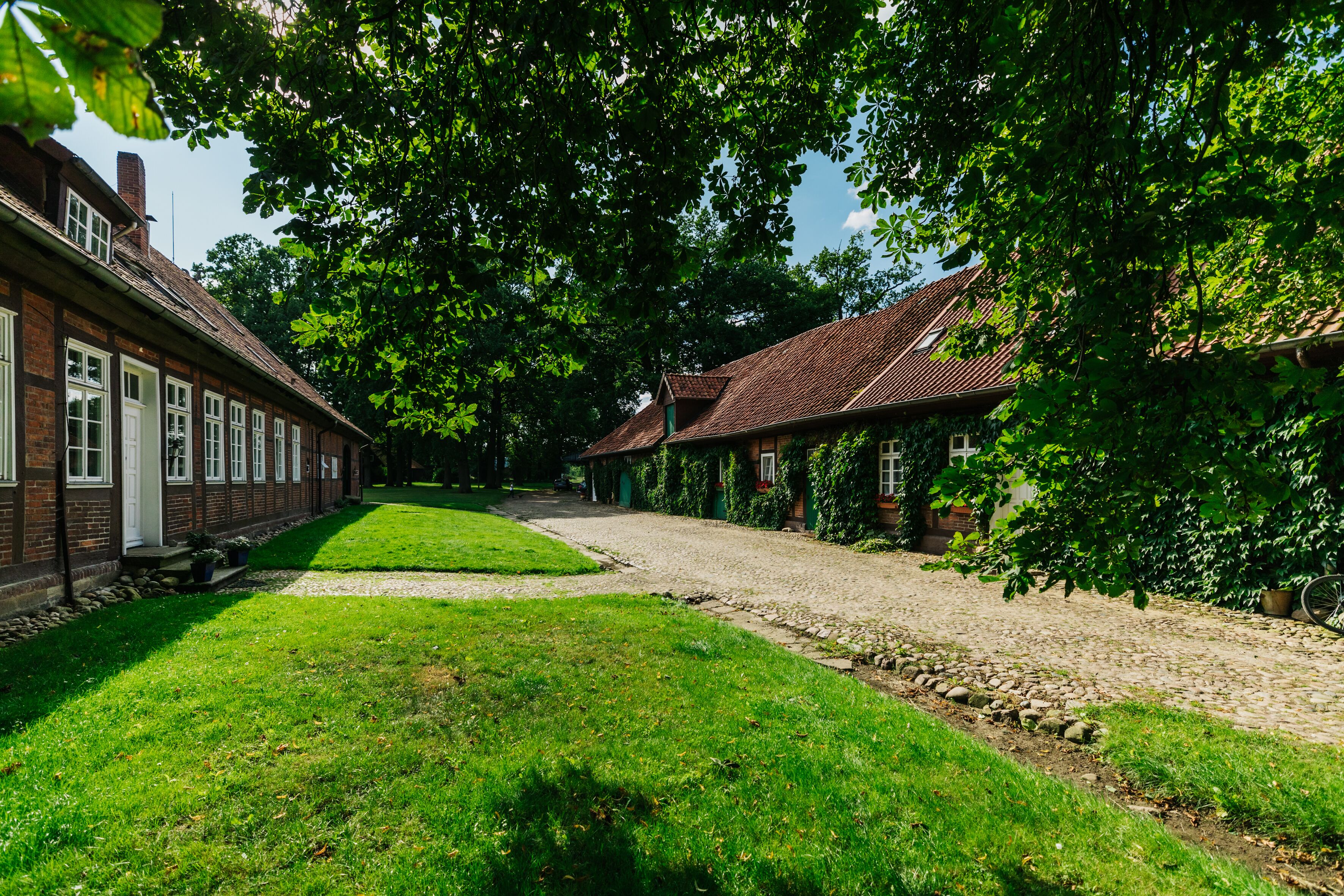 Une rangée de bâtiments traditionnels en briques, avec un chemin pavé et de luxuriantes pelouses verdoyantes.