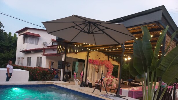 A swimming pool with a patio area, a covered seating area, and a stage for events.