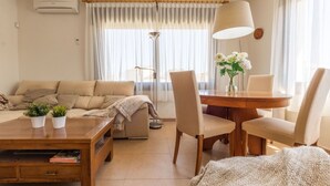 A living room with a sofa, coffee table, and chairs. There is a lamp, a plant, and a vase with flowers. - Cosy apartment for 6 guests with WIFI, A/C, TV and balcony (Torredembarra)