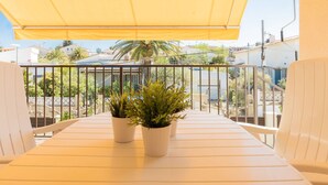 A balcony with a yellow awning, white chairs, and two potted plants. - Cosy apartment for 6 guests with WIFI, A/C, TV and balcony (Torredembarra)