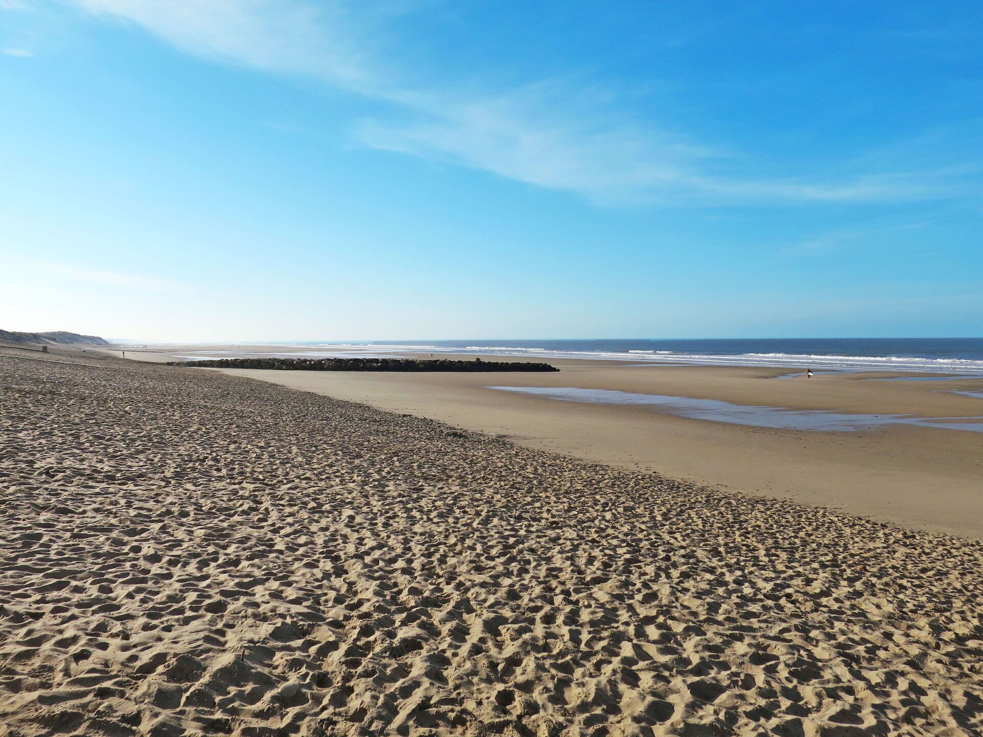 A wide sandy beach with gentle waves and a clear sky.