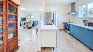 A modern kitchen with a central island, blue cabinets, and a wooden cabinet with glass doors. - Stunning private villa for 6 guests with WIFI, TV, terrace and pets allowed (Montalivet-les-bains)