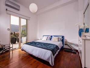 Camera da letto con un grande letto, una porta scorrevole in vetro per un balcone e una lampada a soffitto bianca.