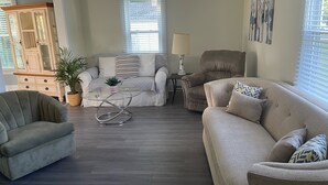 Un salon avec un canapé, un fauteuil et une table basse en verre.