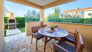 A patio with a round table and chairs, a grill, and a fruit bowl. - Apartment Aster 2 with terrace (Malinska)