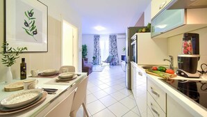 A modern kitchen with a dining area, a refrigerator, a coffee maker, and a dining table set with plates and cups. - Apartment Aster 2 with terrace (Malinska)