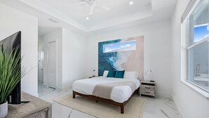 Ein modernes Schlafzimmer mit einem großen Bett, einem Deckenventilator und Blick zum Himmel durch ein Fenster.