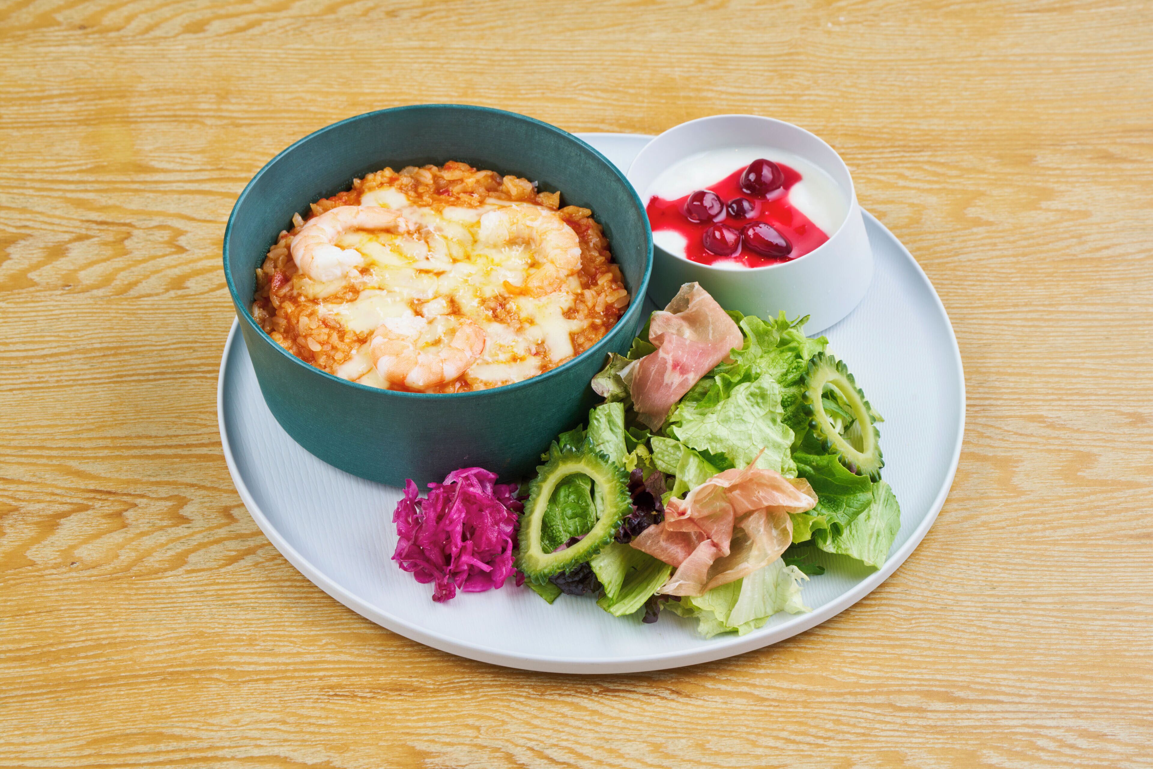 A plate with a bowl of rice, a salad, and a small bowl of yogurt with berries.