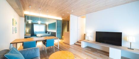 A modern living room with a wooden ceiling, a TV, a sofa, a dining table, and a round coffee table.