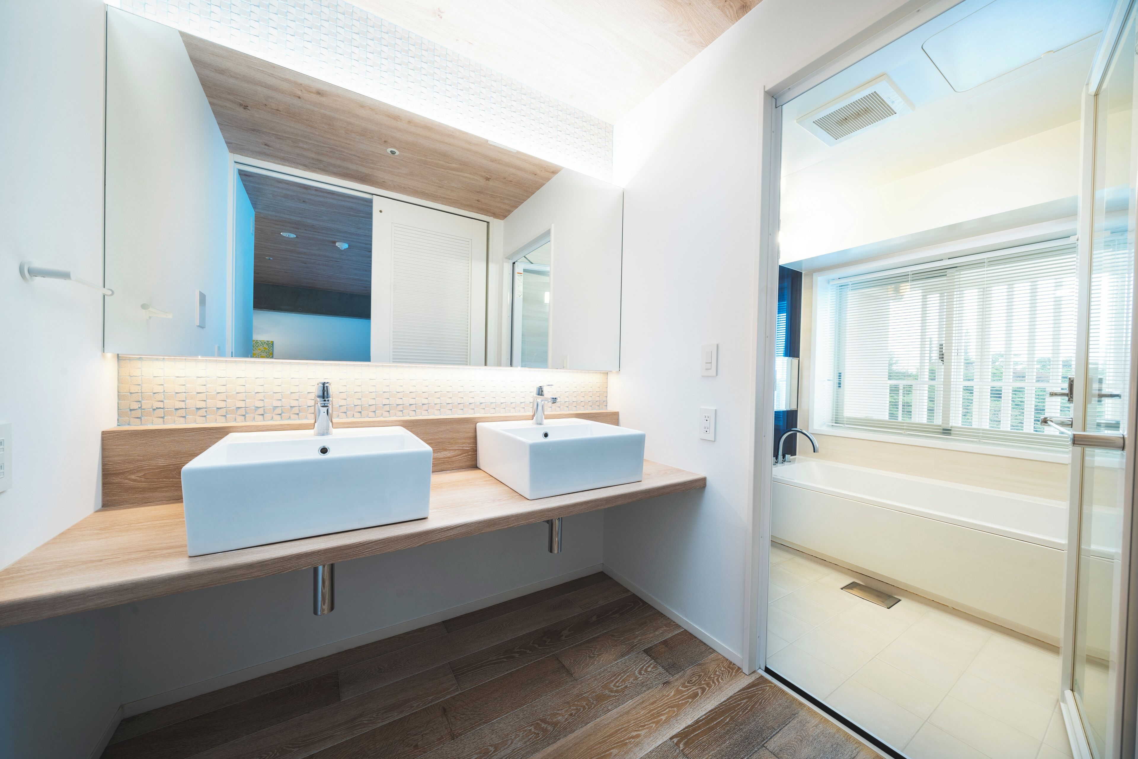 Un baño moderno con dos lavamanos, un espejo grande y una bañera.