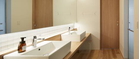 Un baño moderno con dos lavamanos, un espejo grande y suelo de madera.