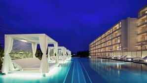 A modern hotel with a pool area, including sun loungers and a covered seating area.