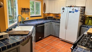 A kitchen with a sink, stove, and white cabinets. - Hideaway Steps to Beaches of Leucadia (Encinitas)