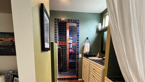 A narrow hallway with a tiled floor leading to a bathroom with a sink and cabinets. - Hideaway Steps to Beaches of Leucadia (Encinitas)