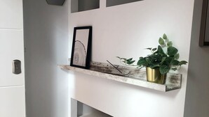 A white wall with a wooden shelf holding a framed picture and a potted plant. - Holidays2Malaga Union Studio Renovated - High Speed WiFi (Málaga)