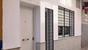 A building facade with a white door, a window with a grid pattern, and a stone-textured wall. - Holidays2Malaga Union Studio Renovated - High Speed WiFi (Málaga)